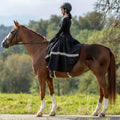 Woman riding a horse in a natural setting with trees in the background